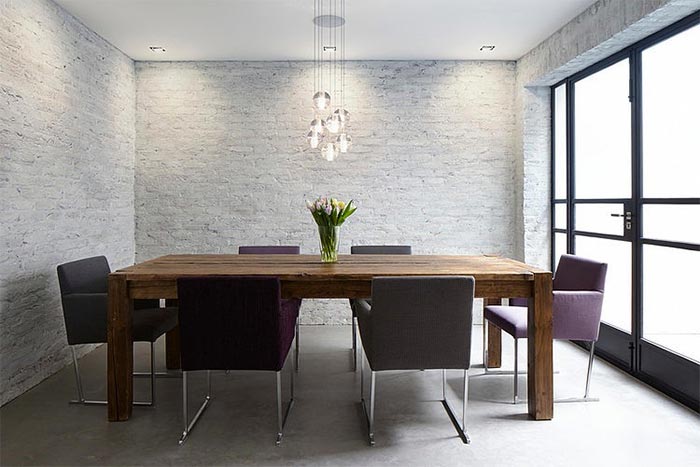 comedor-moderno-sillas-metal-tapizadas-color-berenjena-paredes-ladrillo-visto-blanco